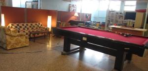 - un salon avec une table de billard et des chaises dans l'établissement Auberge La Petite École de Forillon, à Gaspé