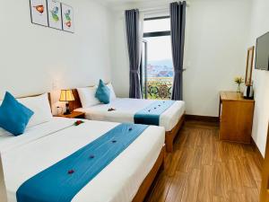 duas camas num quarto de hotel com uma janela em Hotel Phạm Gia Phan Thiết em Phan Thiet
