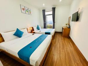 Duas camas num quarto com uma janela grande em Hotel Phạm Gia Phan Thiết em Phan Thiet