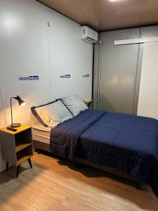 a bedroom with a bed and a nightstand with a blue blanket at Hotel In Box in Irati