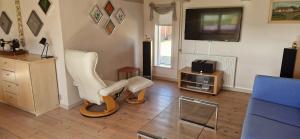 a living room with two white chairs and a television at Lilleledgaard country house in Ringkøbing