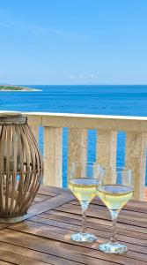 two glasses of white wine sitting on a table overlooking the ocean at Apartment MORE Island Vis in Vis