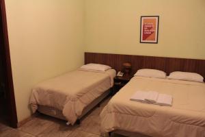 a room with two beds and a picture on the wall at Itaygua Hotel in Ribeirão Preto