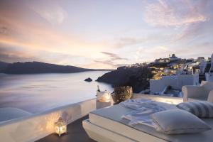 a balcony with a view of the ocean at sunset at Katikies Kirini Santorini - The Leading Hotels Of The World in Oia