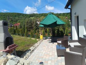 um pátio com cadeiras e um guarda-sol numa casa em Biały Domek em Wisła