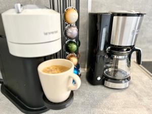 a cup of coffee sitting next to a coffee maker at KorniApartment Zentrum 2 Schlafzimmer Stellplatz in Bautzen