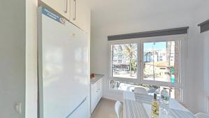 cocina con nevera blanca y ventana en Benalroma a 50 metros de la playa! en Benalmádena