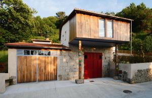 a house with a red door and a garage at O Souto da Aldea Ribeira Sacra Parada de Sil in Parada del Sil