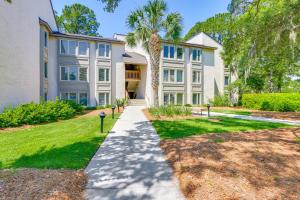 a large white building with a palm tree at Idyllic Sea Pines Villa Walk to the Beach and More! in Hilton Head Island