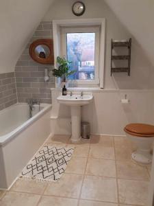 een badkamer met een wastafel, een toilet en een raam bij Lovely 3 Bedroom apartment in Reigate
