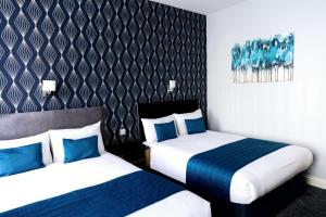 a hotel room with two beds with blue pillows at George Hotel in London