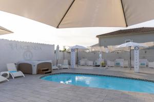 una piscina con sillas y sombrillas junto a un edificio en Hacienda LA Demeure en Saint-Florent