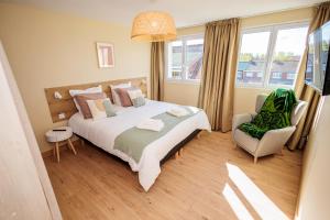 um quarto com uma cama grande e uma cadeira em Appartement 2 chambres et balnéo proximité Dunkerque em Dunkerque