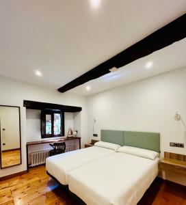 um quarto com uma grande cama branca e um espelho em Apartamentos Rurales L'Arquera em Llanes