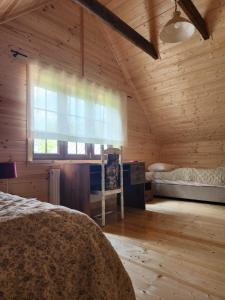 Dormitorio con cama y ventana en una cabaña de madera en Ostoja Wigierski, en Mikolajewo