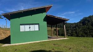 uma casa verde com um telhado no topo de um campo em Chalé Causo Bão em Costas