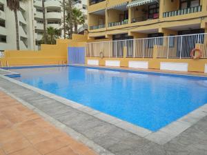 a large blue swimming pool in front of a building at Newly renovated studio 2 min from Playa La Arena in Puerto de Santiago