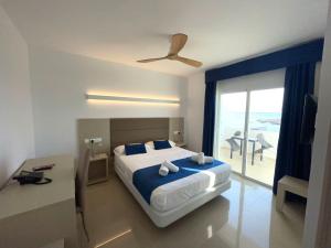 a bedroom with a bed and a view of the ocean at Hotel Roca Bella in Es Pujols