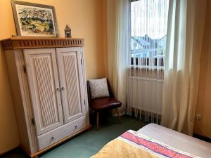 a bedroom with a cabinet and a chair and a window at AUSZEIT für DICH in Himmelkron