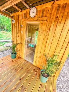 eine Holzhütte mit einer Uhr und zwei Topfpflanzen in der Unterkunft Polana Glamp Sauna&Balia 