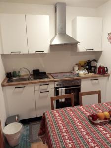 een keuken met witte kasten en een tafel met een tafelkleed bij Apartment Veronika in Vandoies