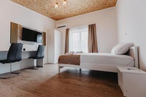 a bedroom with a bed and a desk and a tv at Apartmani Rosa in Nevesinje