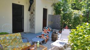 een patio met een bank en stoelen in een tuin bij Stomio 4 Seasons Relaxing Apartment in Stómion