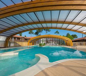 a large swimming pool with a wooden ceiling at Cottage prenium tout confort in Parentis-en-Born