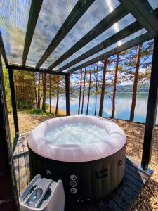 a hot tub in a gazebo with a view of the water at Nomad Lake Cabins in Rugineşti