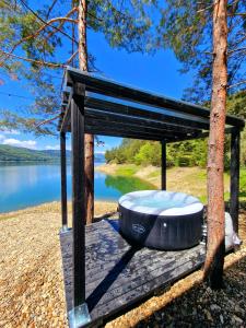 a hot tub on a deck next to a lake at Nomad Lake Cabins in Rugineşti