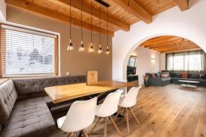 sala de estar con mesa de madera y sillas blancas en Jägerlodge Apartments, en Ladis