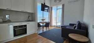 a kitchen and living room with a couch and a table at Lighthouse Apartment Šventosios Vartai in Palanga