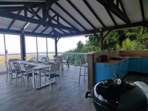 een patio met een tafel en stoelen en een keuken bij Villa Lidoam vue mer imprenable in Le Vauclin