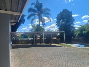 a basketball hoop in a driveway with a palm tree at Sunset Guest House in Roodepoort