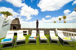 a group of chairs and an umbrella on the grass at Casa Federico in Puerto del Carmen