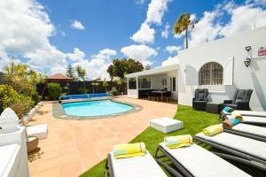 a backyard with a swimming pool and lounge chairs at Casa Federico in Puerto del Carmen