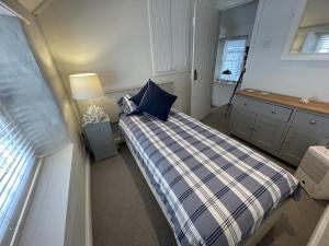 une chambre avec un lit avec un oreiller bleu et une fenêtre dans l'établissement Beach Hill Cottage, à Portloe