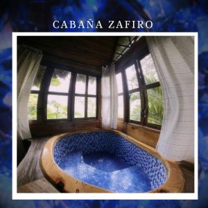 bañera de hidromasaje en una habitación con ventanas en EcoHostal Rio Piedra en El Zaino