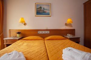 a bedroom with a large yellow bed with two lamps at Acropole Delphi City Hotel in Delphi