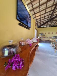 uma longa mesa de madeira com flores roxas em cima em Villa Garcez em Jaguaripe