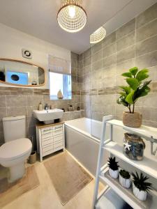 Un baño con bañera, inodoro y lavabo. en Seaside beach themed home with garden and driveway, en Lytham St Annes