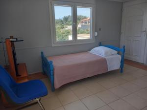 a bedroom with a bed and a chair and a window at Mountain & Sea View VILA in Áyios Andréas