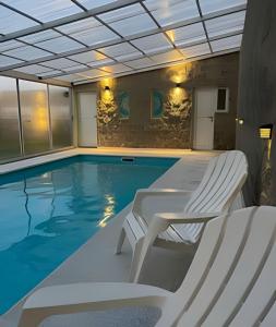 a swimming pool with two white chairs and a swimming pool at El Galpon de Solana in Puerto Madryn