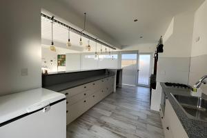a kitchen with white cabinets and a wooden floor at El Galpon de Solana in Puerto Madryn