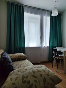 ein Schlafzimmer mit grünen Vorhängen, einem Tisch und einem Bett in der Unterkunft Hostel&ApartServices Viennna The Tidy Apartment in Wien