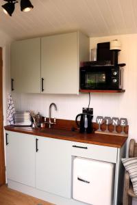 uma cozinha com armários brancos e um micro-ondas em Cobo Cottage em Chichester