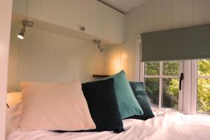 ein Schlafzimmer mit einem Bett mit Kissen und einem Fenster in der Unterkunft Cobo Cottage in Chichester
