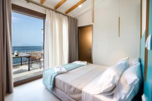 a bedroom with a bed and a balcony with a view at Vela Bianca Suites in Limenaria