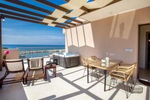 a patio with a table and chairs and the ocean at Vela Bianca Suites in Limenaria