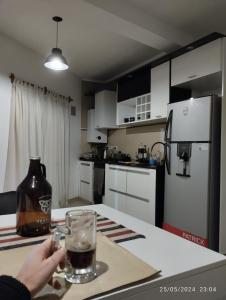 eine Person, die ein Glas Getränk auf einer Küchentheke hält in der Unterkunft DEPARTAMENTO 2 DOR. ZONA PARQUE CON JACUZZI in Paraná